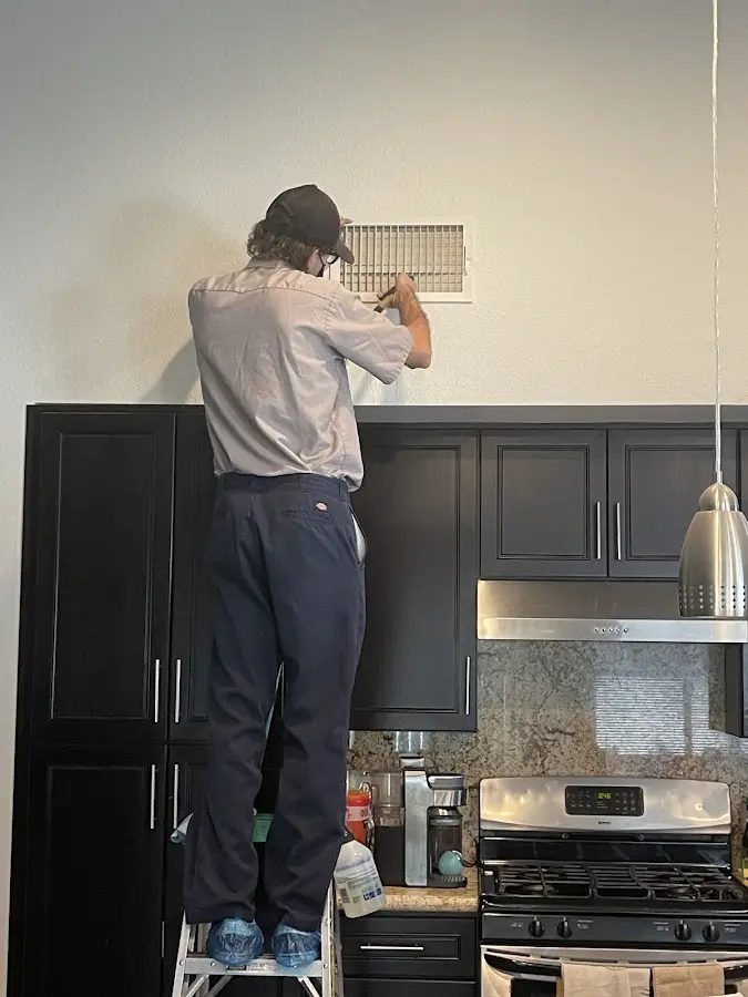 Technician inspecting an air vent during HVAC service in Palm River-Clair Mel